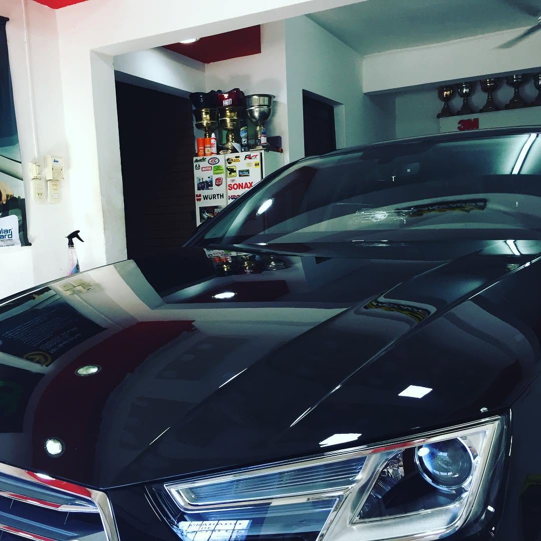 Audi A4 negro con parabrisas y cristales polarizados dentro del taller