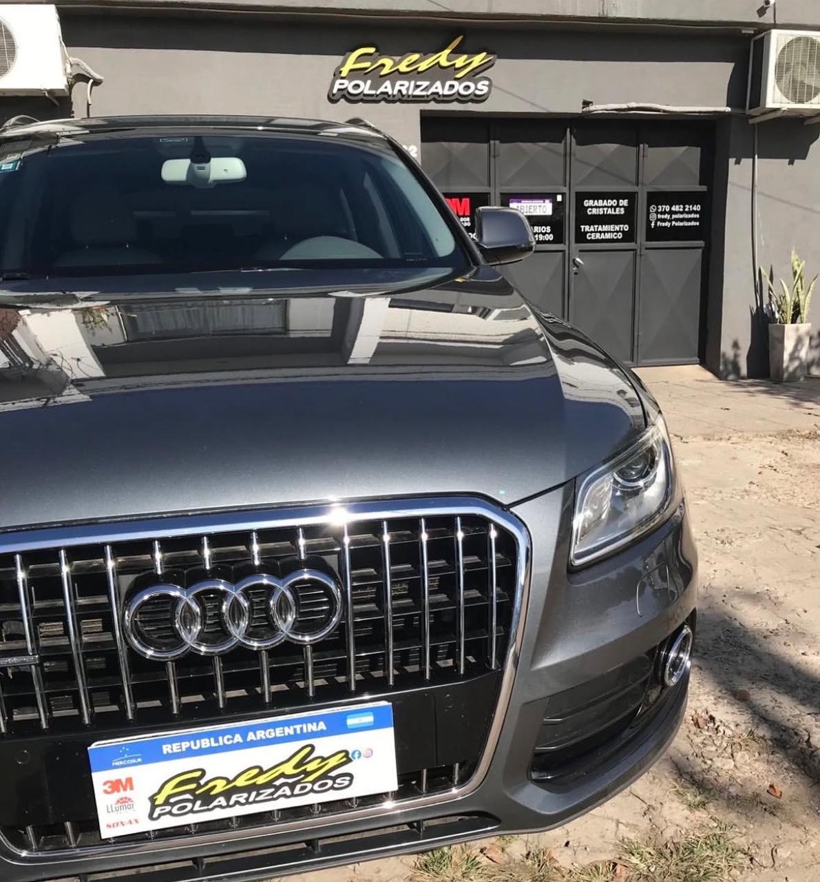 Audi Q5 gris con cristales polarizados en la puerta del local de Fredy Polarizados