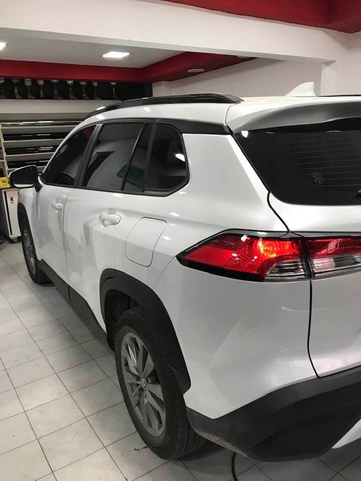 Toyota Corolla Cross blanca con cristales polarizados, vista trasera en el taller