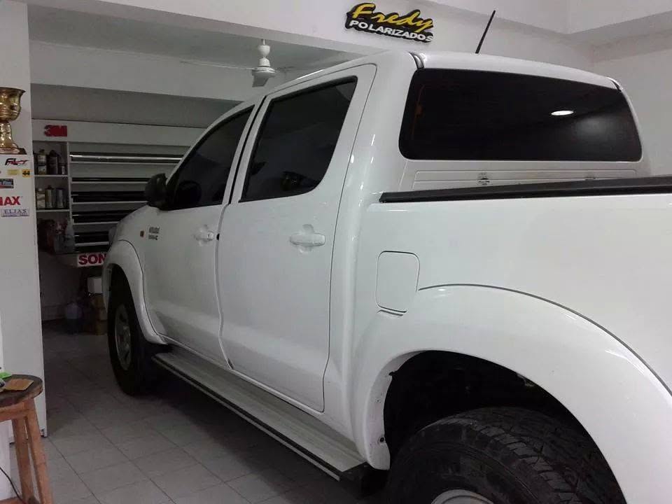 Toyota Hilux blanca con cristales polarizados bajo el cartel de Fredy Polarizados