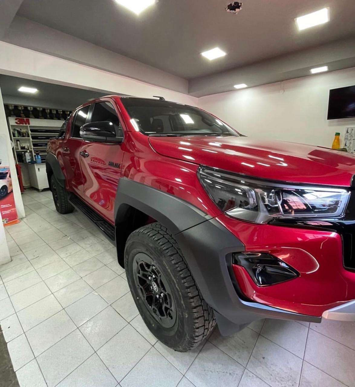 Camioneta Hilux roja con cristales polarizados terminada en el taller de Fredy Polarizados